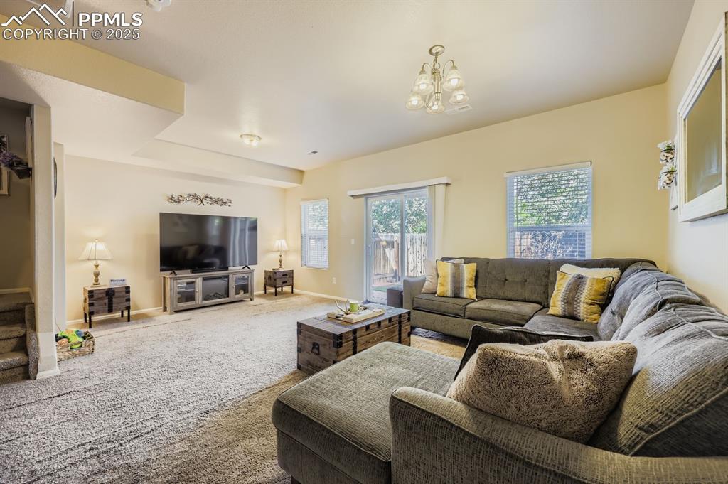 Image 5 of 27: Living area with carpet floors and a chandelier