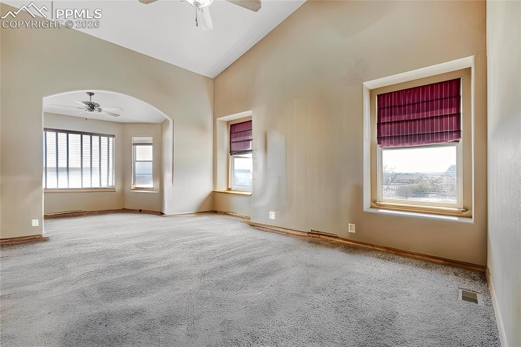 Image 14 of 31: Spacious room featuring vaulted ceilings, light gray carpet, and an arched