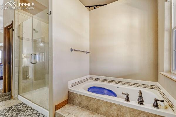 Image 18 of 31: Bathroom featuring a built-in jetted tub with decorative tile surround, a s
