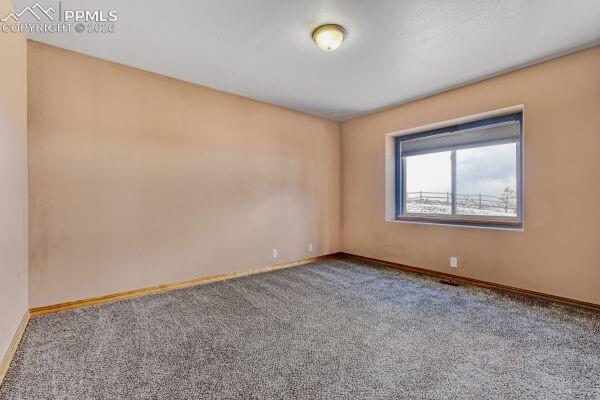 Image 19 of 31: Spacious room featuring neutral-toned walls, grey carpet flooring, and a la