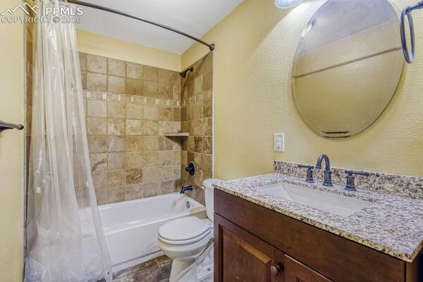Image 24 of 31: Bathroom featuring a tub/shower combination with tile surround, a dark wood