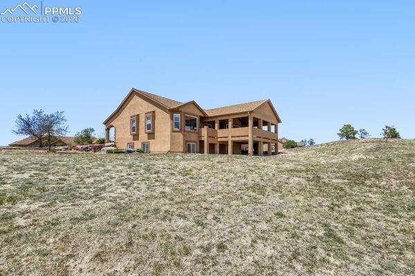 Image 28 of 31: Stucco exterior with multiple windows, featuring a covered upper-level deck