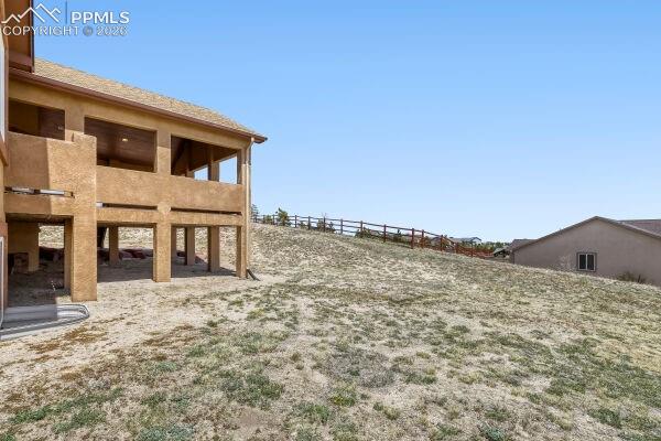 Image 29 of 31: Expansive sloped property featuring a covered patio, a covered balcony, and