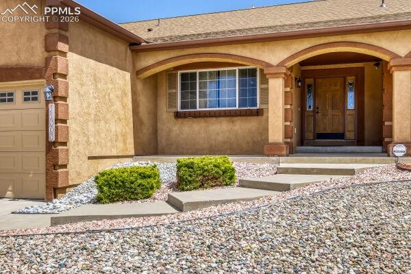 Image 3 of 31: Stucco exterior featuring a covered entry with arched details and a wooden