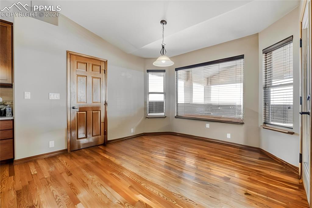 Image 9 of 31: Dining area featuring wood-finish flooring, a six-panel wood door, and a ba