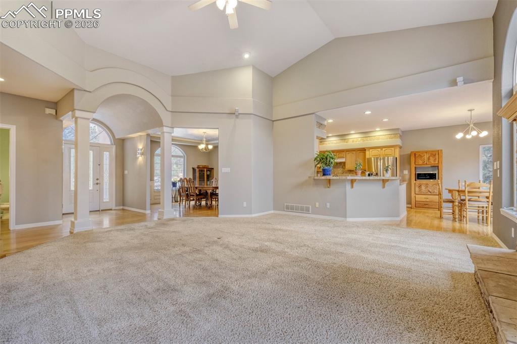 Image 10 of 50: living room with suspended lighting, light colored carpet, ornate columns, 