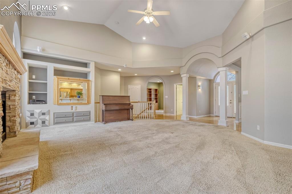 Image 11 of 50: living room with built in features, carpet floors, ornate columns, arched w