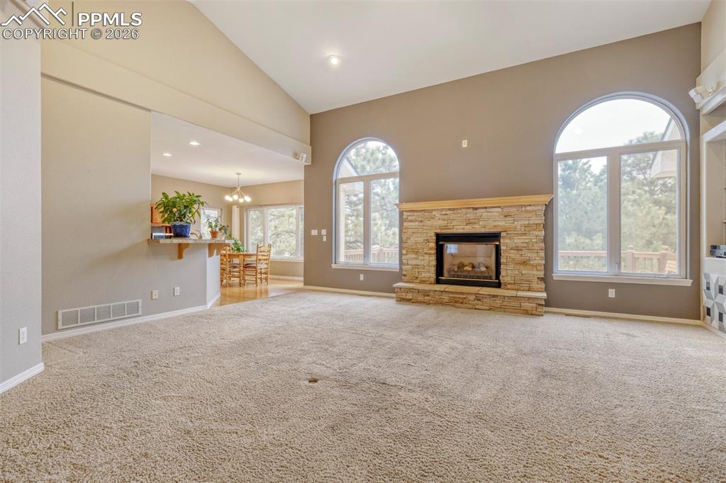 Image 12 of 50:  living room featuring a fireplace, light colored carpet, vaulted ceiling, 
