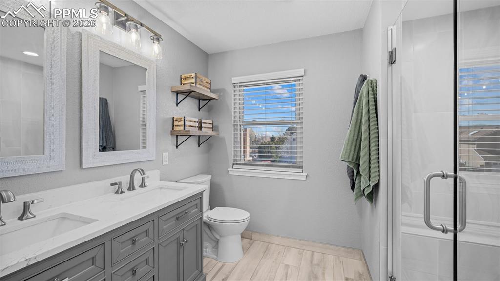 Image 16 of 44: Bathroom with a stall shower, double vanity, and light wood-style floors