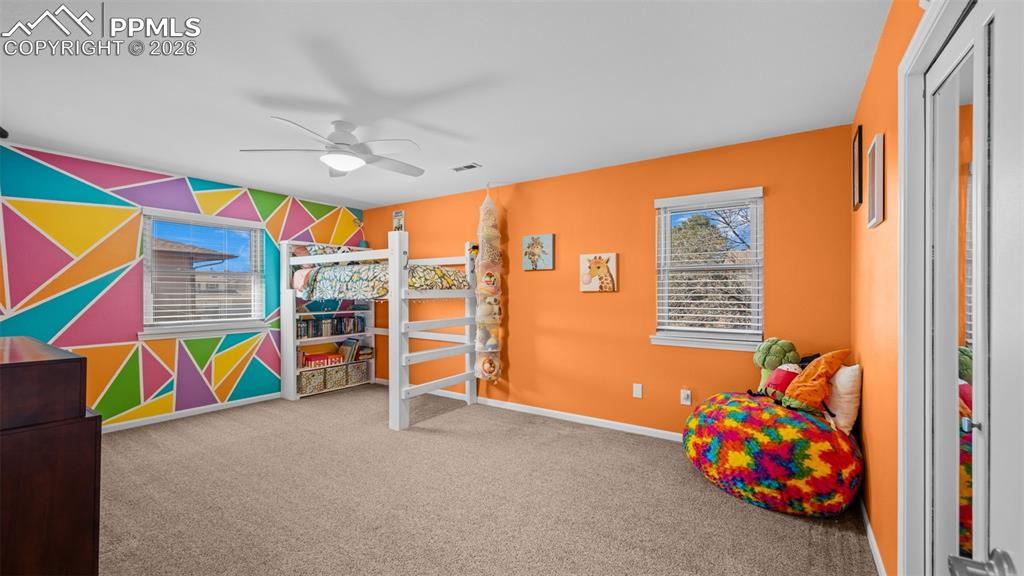 Image 20 of 44: Bedroom with light colored carpet, ceiling fan, and an accent wall