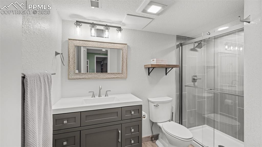 Image 26 of 44: Full bath featuring vanity, a shower stall, a textured ceiling, and a textu