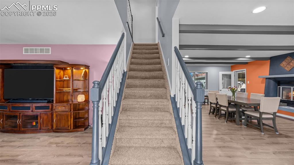 Image 6 of 44: Stairway featuring wood finished floors, a glass covered fireplace, and rec