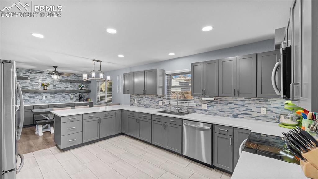Image 7 of 44: Kitchen with backsplash, stainless steel appliances, gray cabinetry, a peni