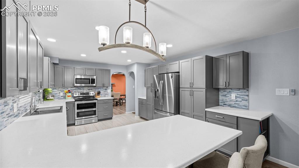 Image 8 of 44: Kitchen featuring gray cabinets, arched walkways, a peninsula, stainless st