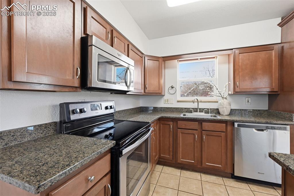 Image 8 of 32: Wood cabinets and stone countertops in the kitchen