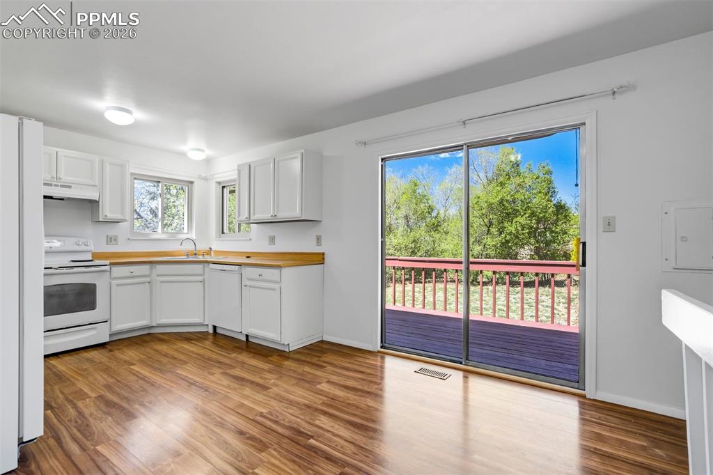 Image 11 of 50: The property features a kitchen with white cabinetry, a white stove, and li