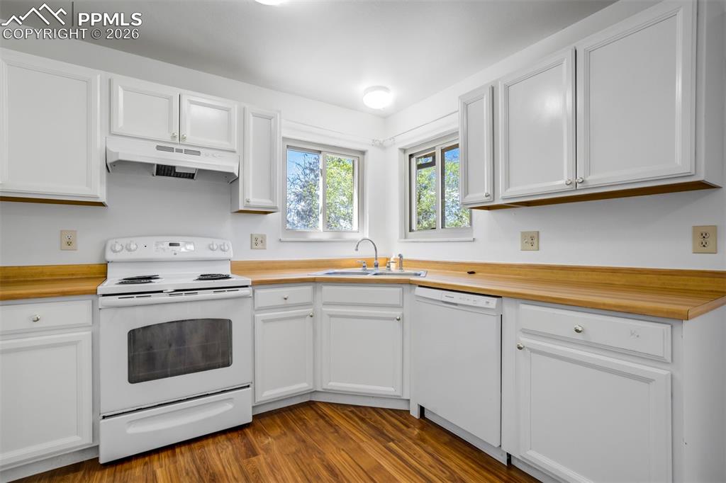 Image 14 of 50: The property features a kitchen with white cabinetry, wood-look countertops