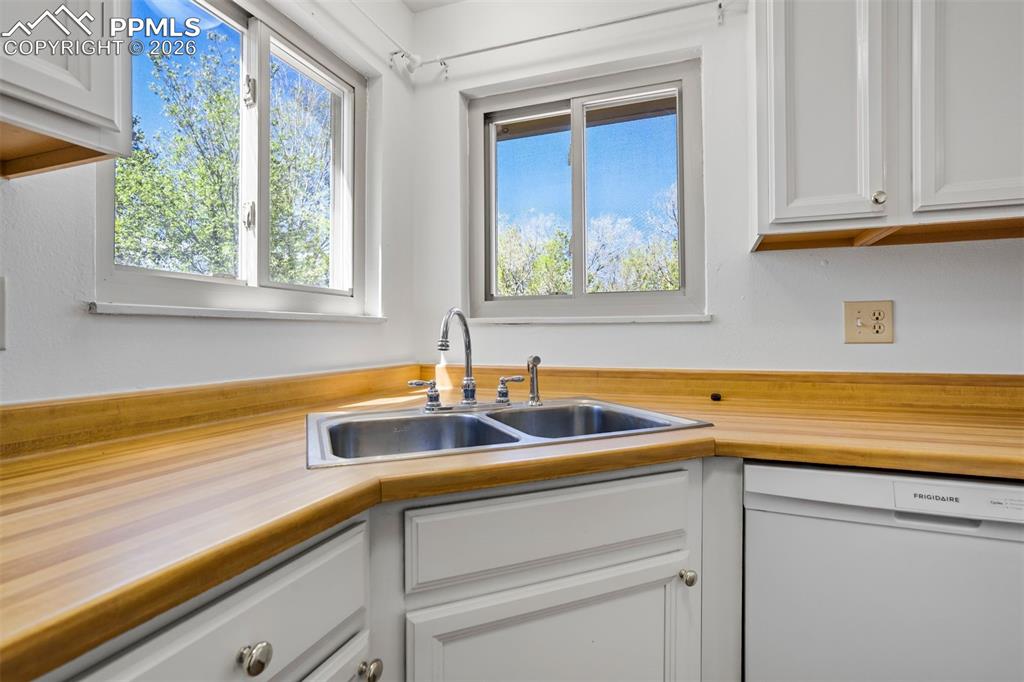 Image 15 of 50: The kitchen features a double stainless steel sink, light wood countertops,