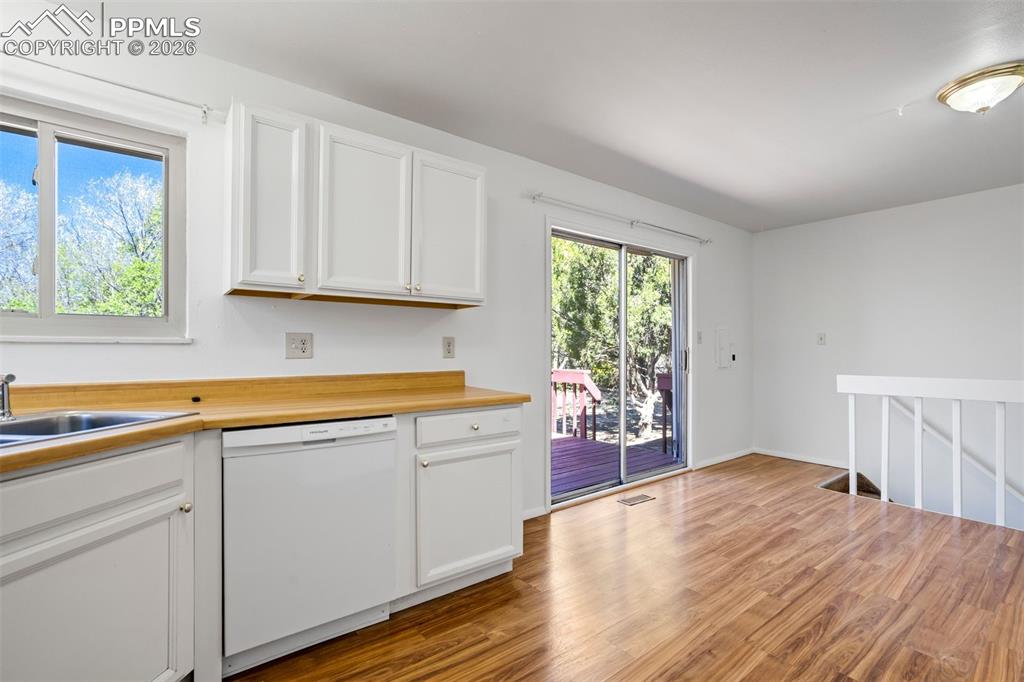 Image 16 of 50: The kitchen features white cabinetry and wood-look countertops