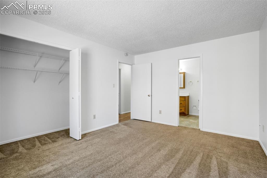 Image 18 of 50: This room features carpeted flooring, white walls, and a closet with shelvi