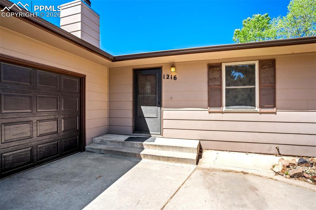 Image 2 of 50: The property features a dark brown garage door, a front entry with concrete