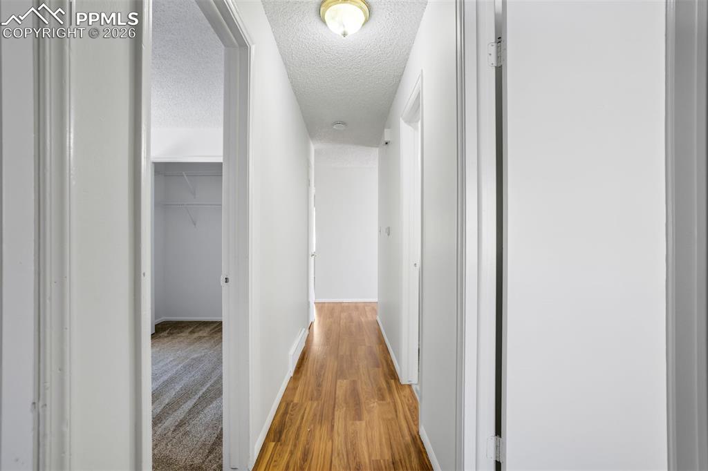 Image 24 of 50: Hallway featuring wood flooring, white walls, and a ceiling light fixture