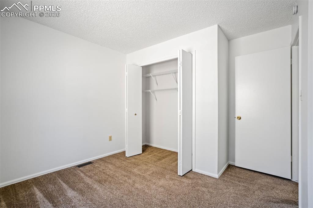 Image 26 of 50: The property features a room with light brown carpet flooring and white wal