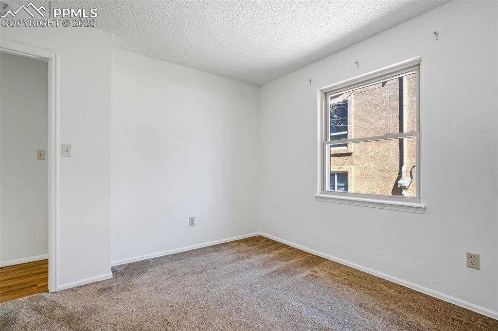 Image 28 of 50: This room features neutral-toned carpet, white walls, and a window providin