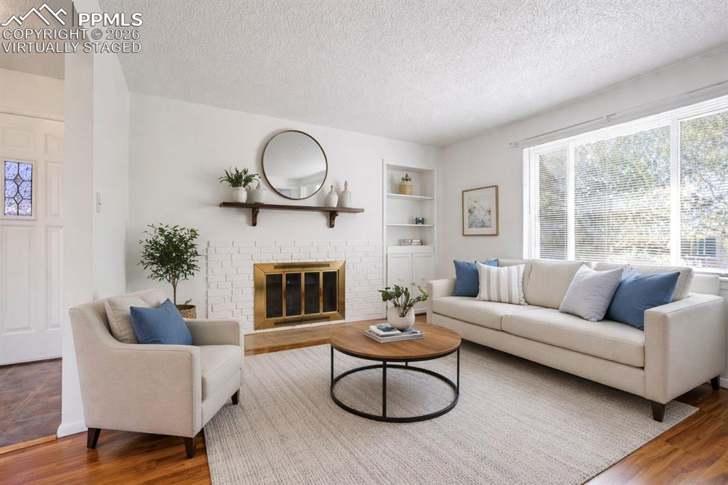 Image 3 of 50: Virtually Staged - The living area features hardwood floors, a white brick 