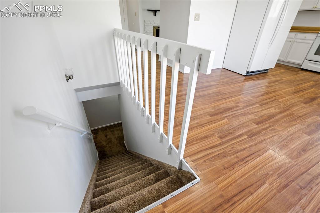 Image 36 of 50: The property features hardwood style flooring and a carpeted staircase with