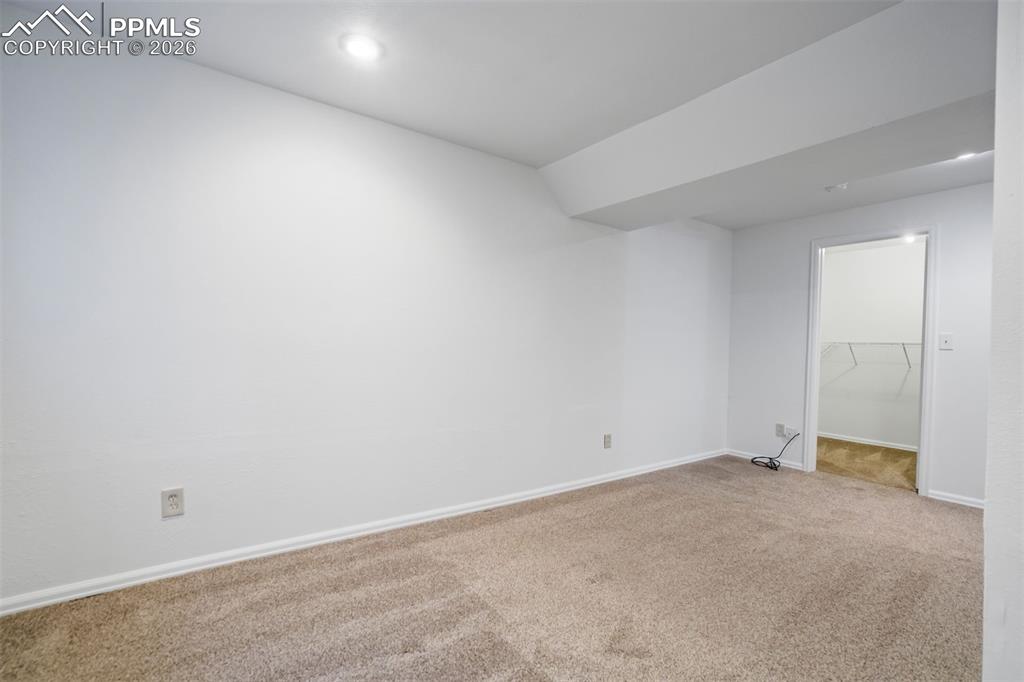 Image 39 of 50: This room features clean white walls, neutral carpeted flooring, and a rece
