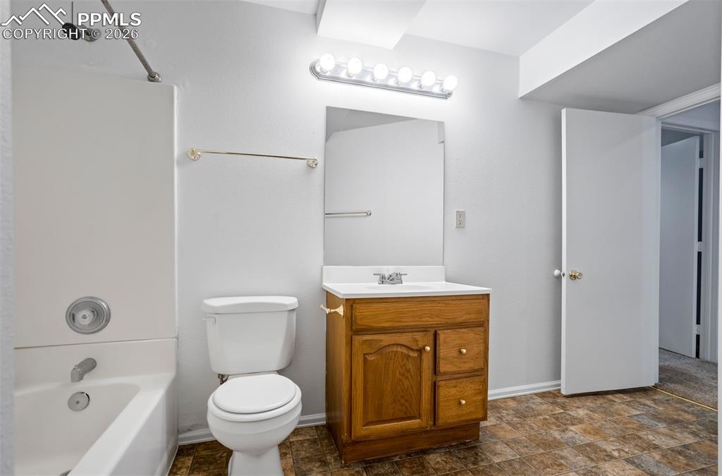 Image 42 of 50: This bathroom features a white bathtub with a shower, a toilet, and a vanit