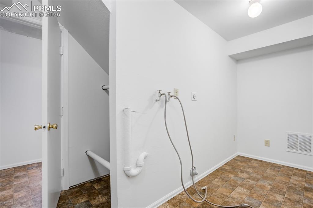 Image 43 of 50: Utility area with tiled flooring, white walls, and a ceiling-mounted light 
