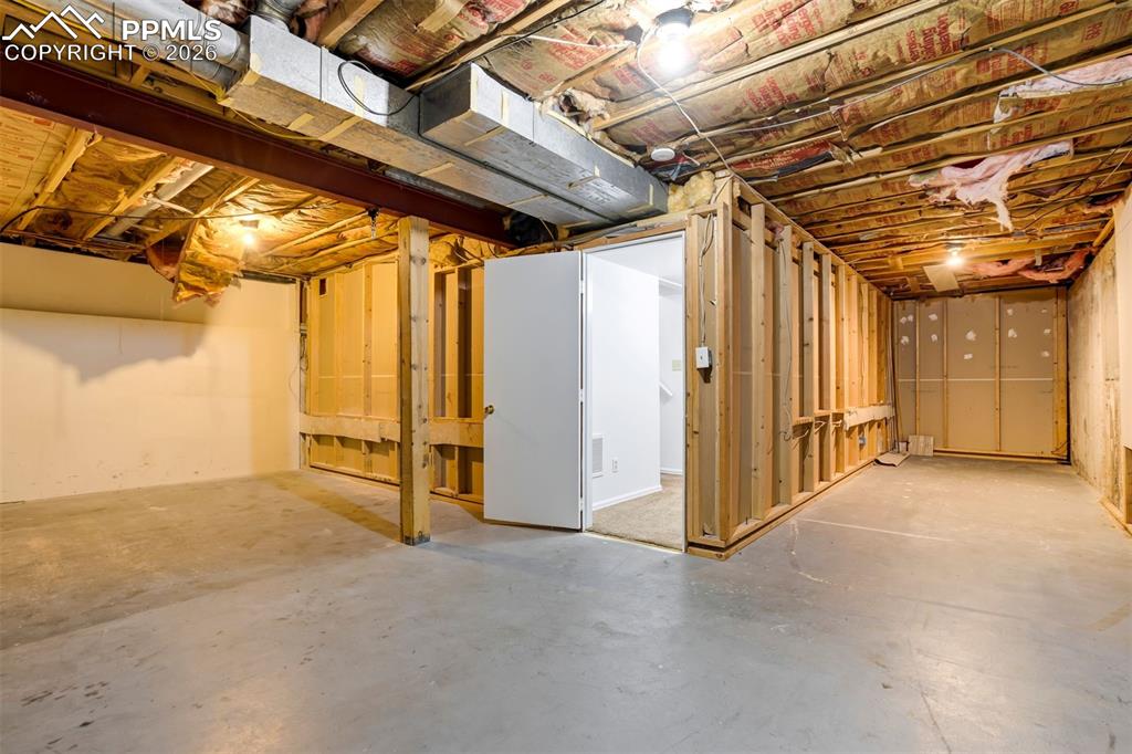 Image 45 of 50: The property features an unfinished basement with exposed wooden joists, co