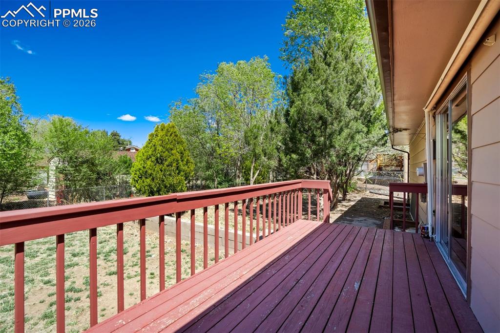 Image 46 of 50: The property features a red-stained wooden deck with railings, offering out