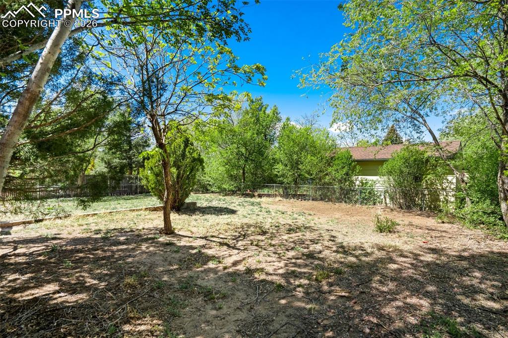 Image 47 of 50: Expansive yard featuring mature trees and green foliage, with partial views