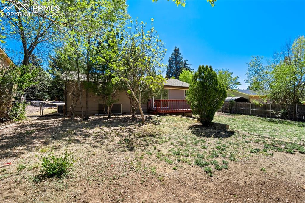 Image 48 of 50: The property features a spacious yard with mature trees and a wooden deck, 