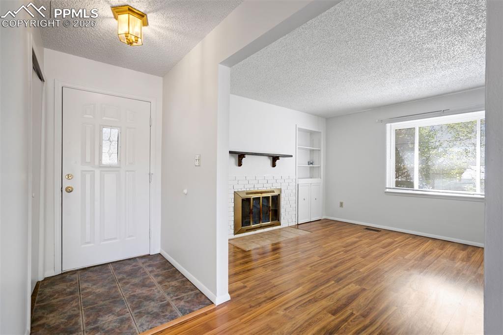 Image 7 of 50: Entryway with tiled flooring and a white front door, opening into a living 
