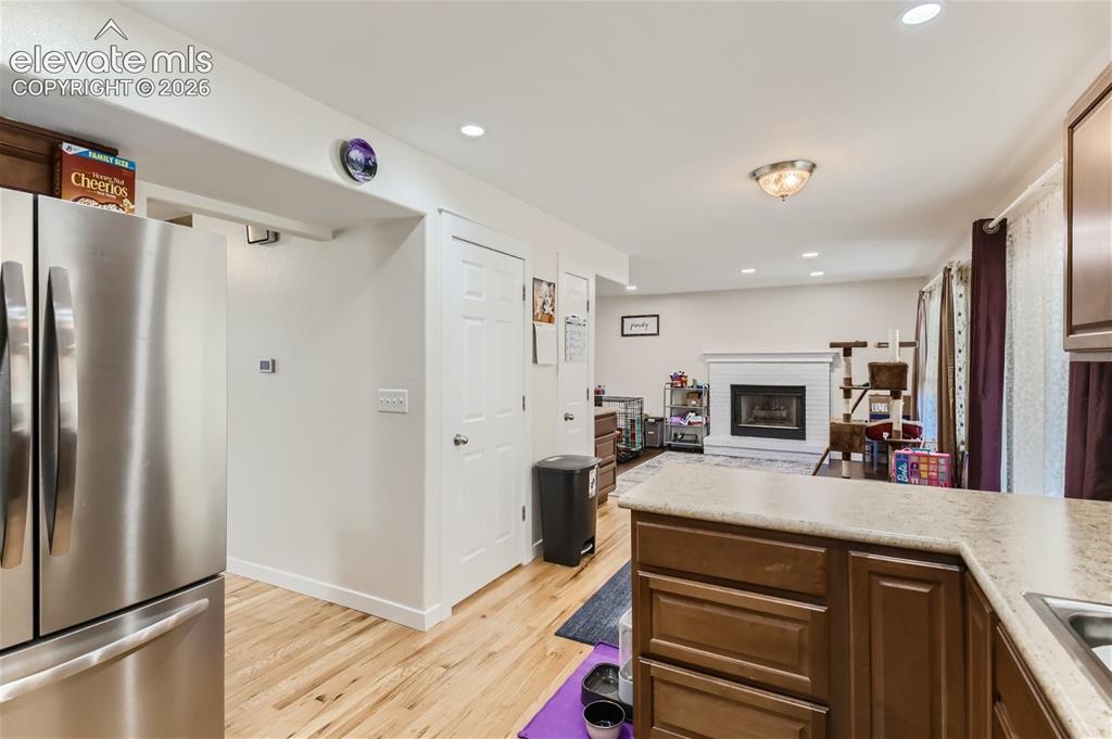 Image 10 of 49: Stainless steel refrigerator, wood-finish flooring, white paneled doors, bu