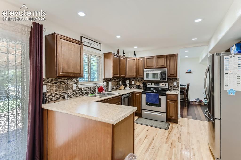 Image 11 of 49: Kitchen featuring wood cabinetry, stainless steel appliances, a mosaic tile