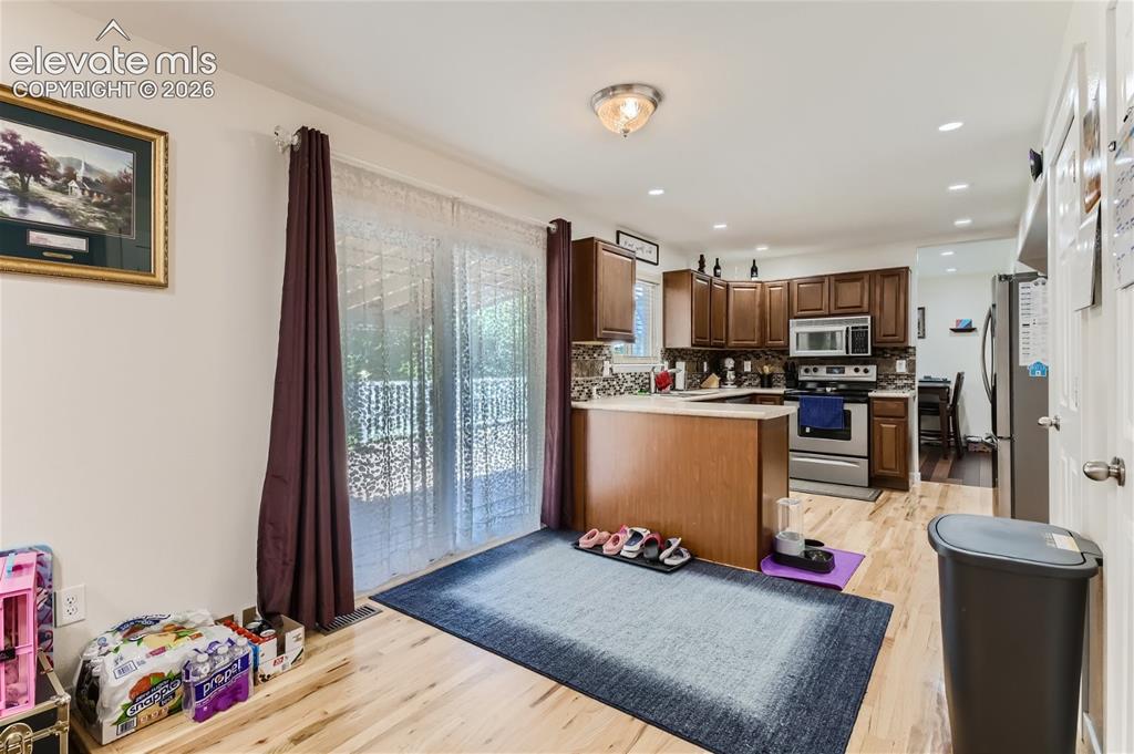 Image 13 of 49: Kitchen with wood-finish flooring, dark wood cabinetry, stainless steel app