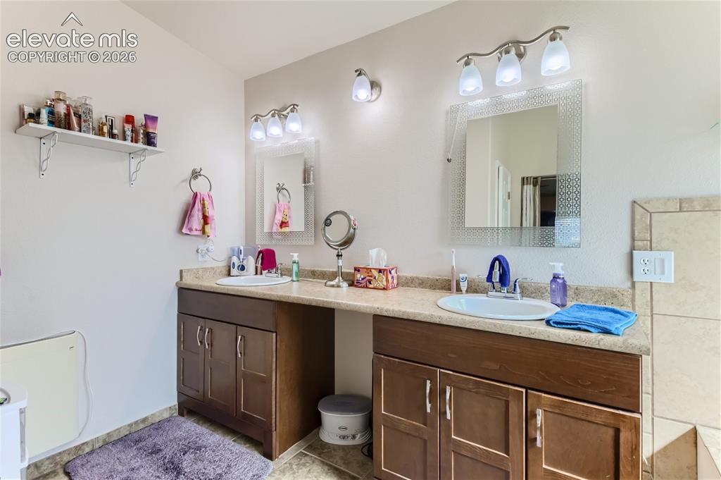 Image 21 of 49: Dual sink vanity with wood-finish cabinetry, light-toned countertop, and in