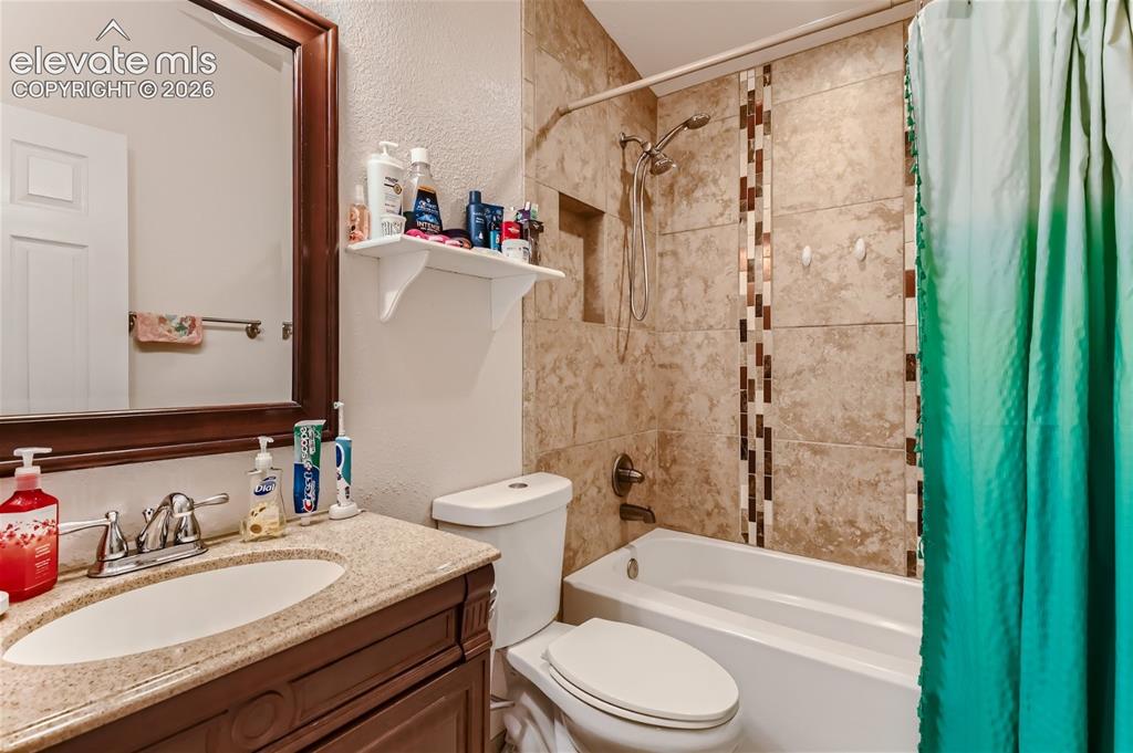 Image 27 of 49: Bathroom featuring a wood-finish vanity with a light-toned countertop, an u