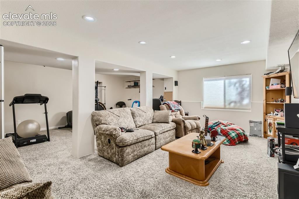 Image 28 of 49: Recessed lighting, light-colored walls, and neutral carpeting create a vers