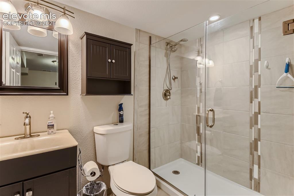 Image 32 of 49: Frameless glass shower enclosure with tiled surround, vanity with an integr