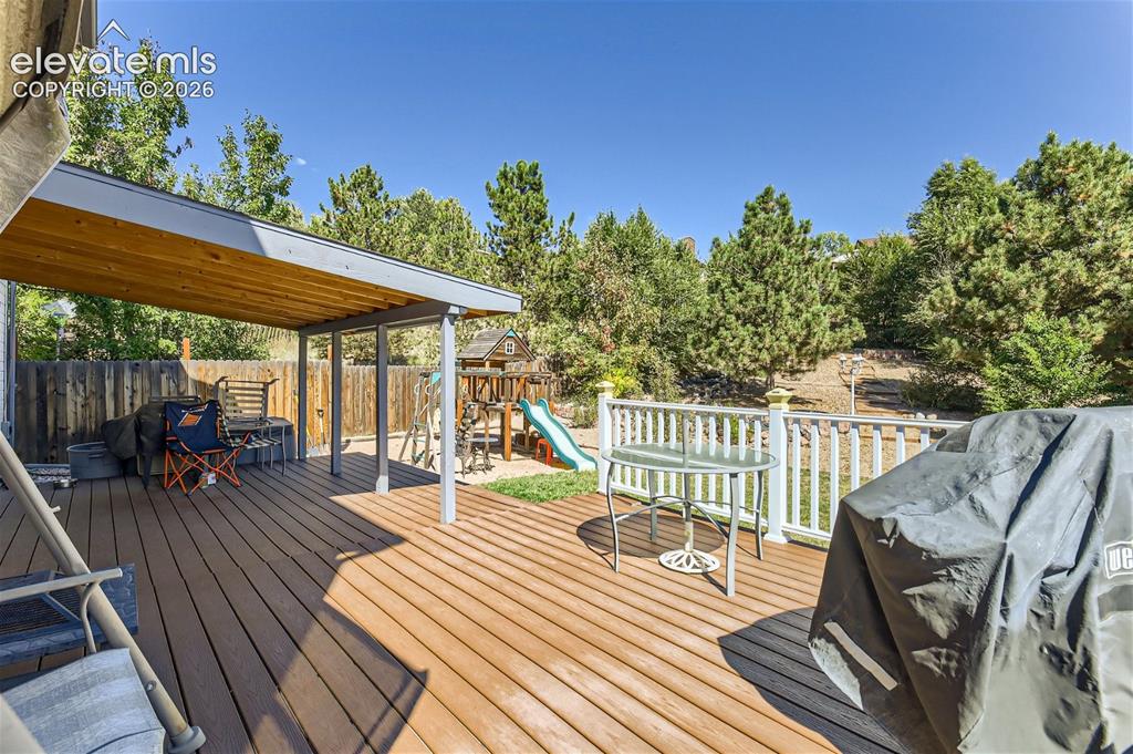 Image 36 of 49: Expansive outdoor deck with composite decking, covered patio area, white ra