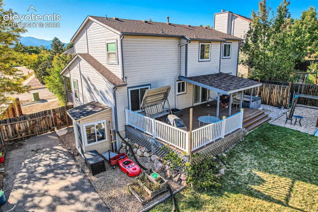 Image 37 of 49: Multi-level deck with white railings, featuring a covered patio area and st