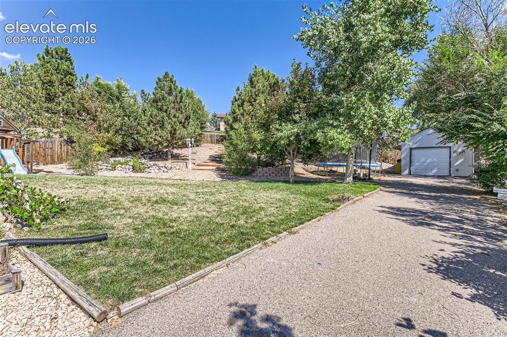 Image 39 of 49: Expansive gravel driveway leading to a detached garage