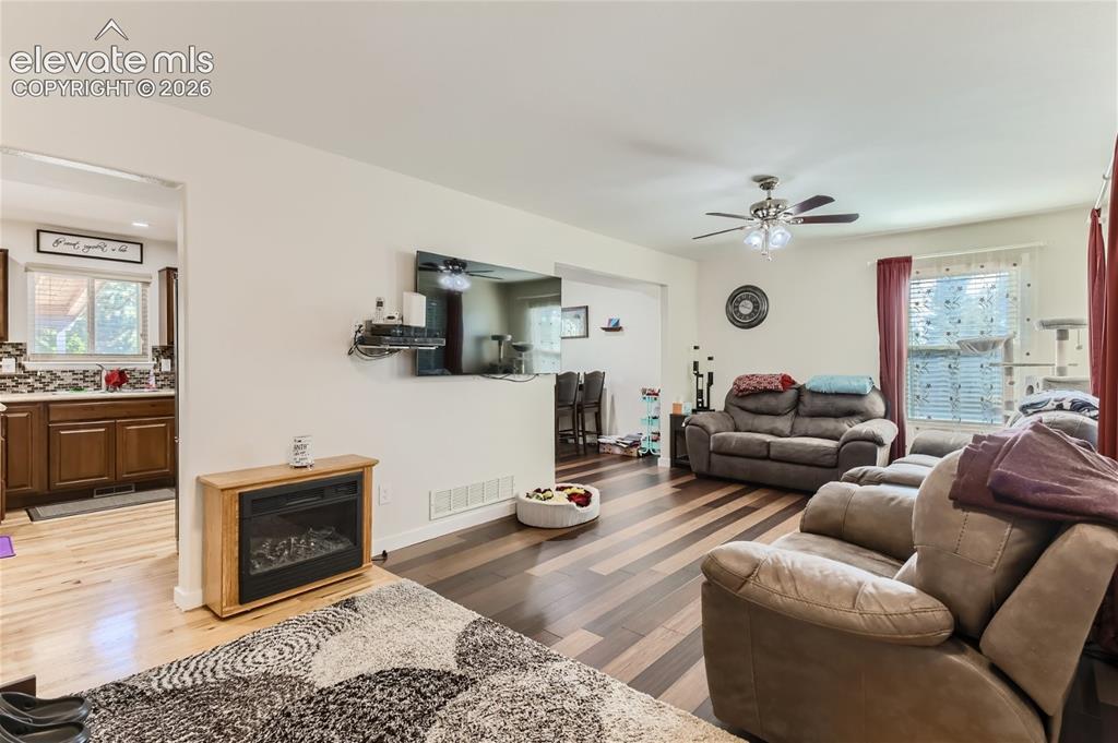 Image 4 of 49: Wood-finish flooring throughout, with a ceiling fan featuring integrated li