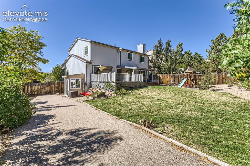 Image 40 of 49: Expansive backyard with a manicured lawn, wood fencing, and a gravel pathwa